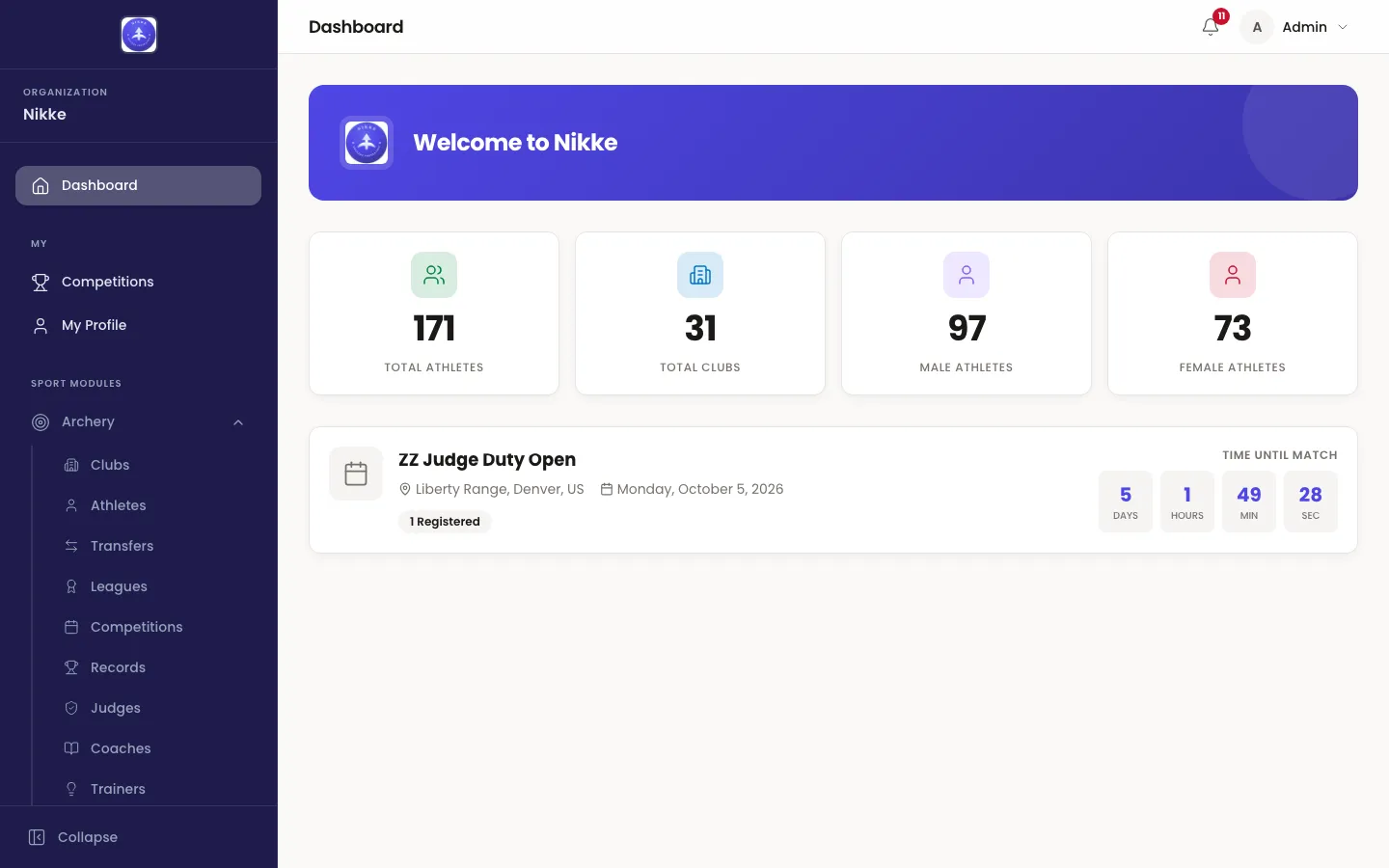 The Velos dashboard: a welcome banner naming your federation, club or academy, four tiles counting total athletes, total clubs, male athletes and female athletes, and a card for the next competition showing its venue, dates, number of registered entries and a countdown.